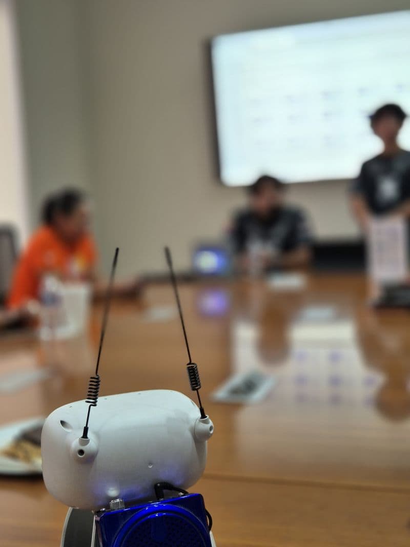 Robot Lumi sobre la mesa de una reunión, con sus dos antenas en primer plano